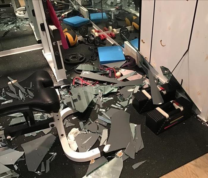 Home gym covered in broken glass from large mirror