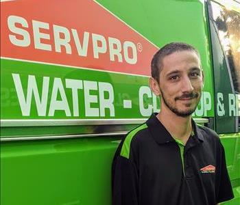 Male employee Steven standing next to green SERVPRO van