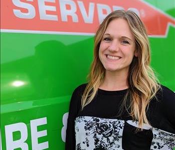 Female employee Molly standing in front of green SERVPRO van