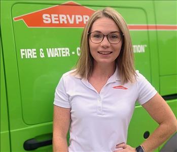 Female employee Katie standing in front of green vehicle
