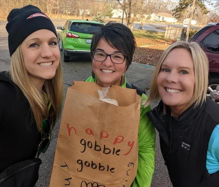Three SERVPRO ladies standing with brown paper bag