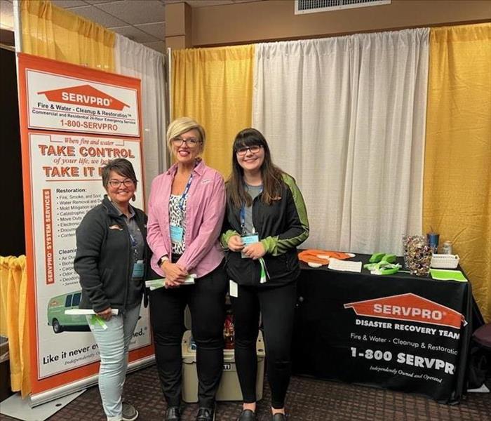 Three SERVPRO representatives standing in front of display booth