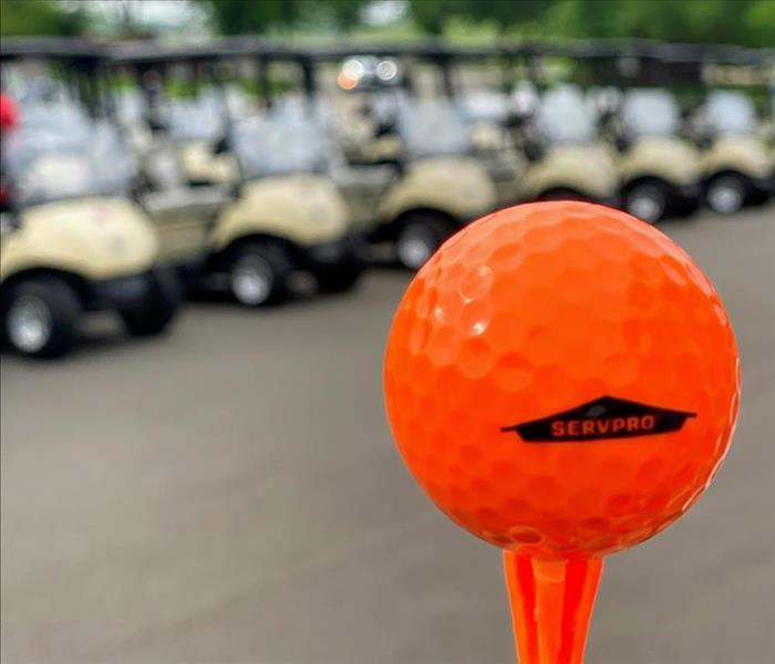SERVPRO golf ball on orange tee in front of golf carts