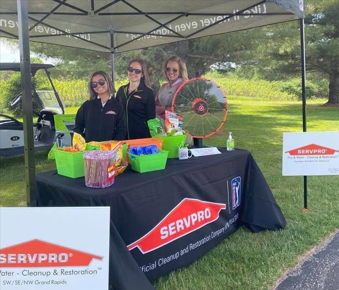SERVPRO Marketing Ladies standing behind booth at MAA Golf Outing